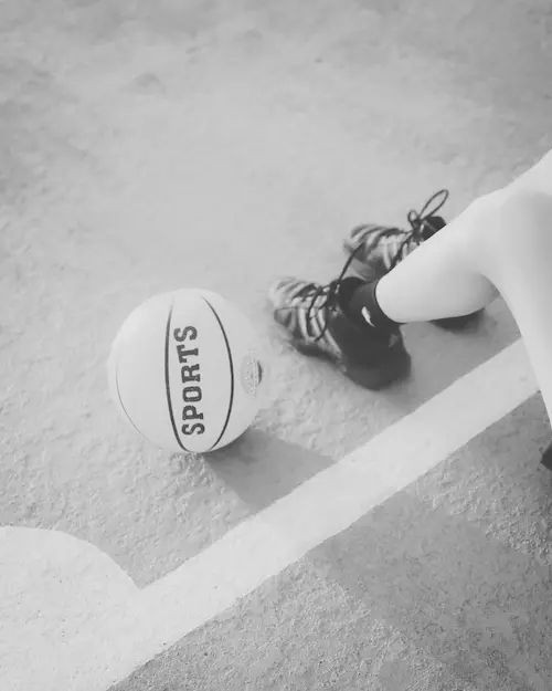 Basketball resting on the ground beside a seated player on an outdoor court.