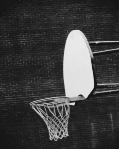 Weathered basketball hoop and backboard against a concrete wall.