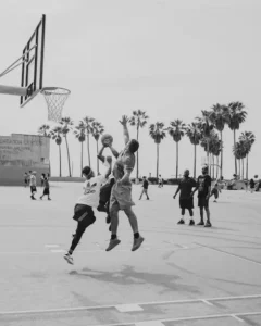 Basketball player jumping to take a shot on an outdoor court.