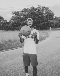 Person standing on a road holding a basketball.